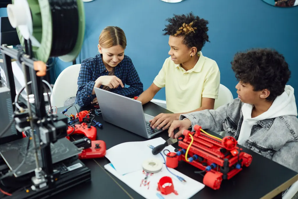Three children working on a laptop beside a 3D printer.